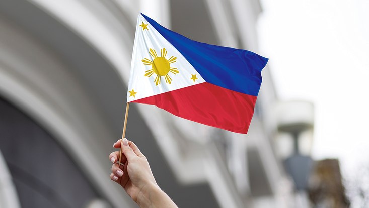 a hand holding a Philippine flag